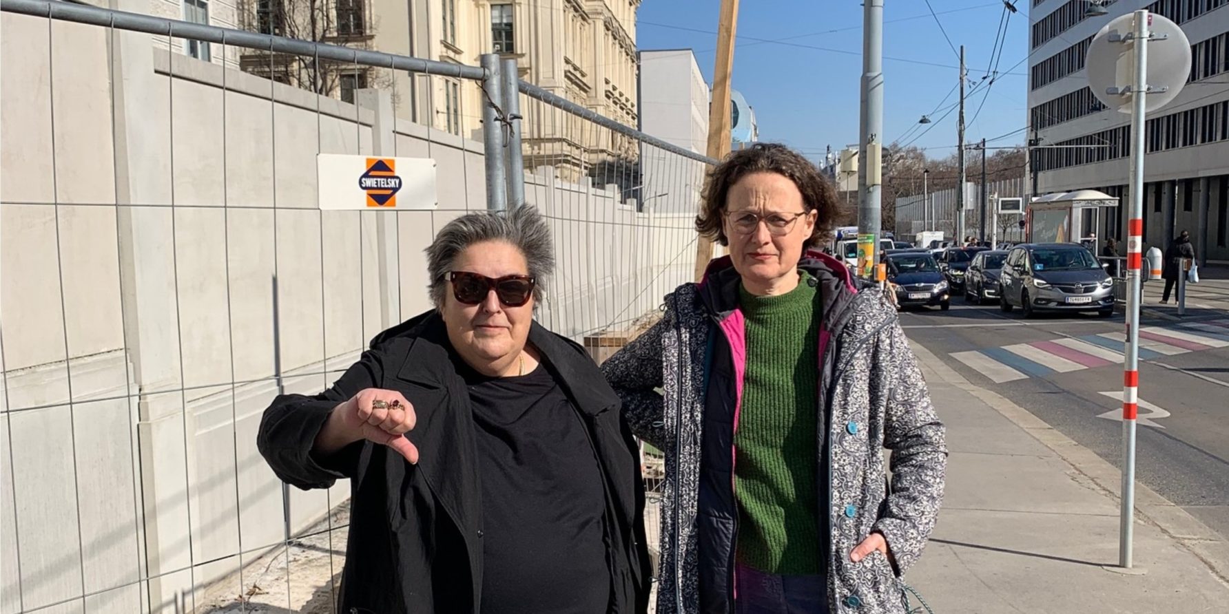 Christa Schmid und Josefa Molitor-Ruckenbauer zeigen Daumen nach unten vor im Bau befindlicher Mauer